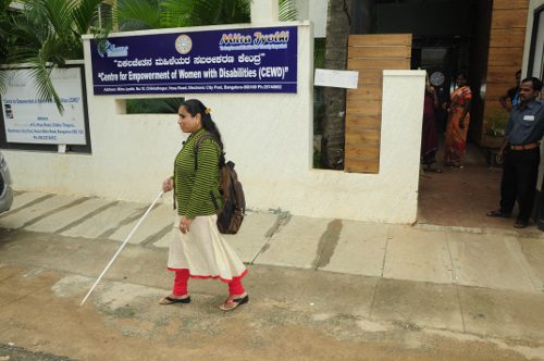A woman walking down the street with a cane.