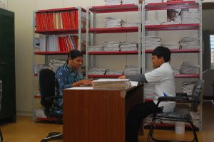 a couple of men sitting at a desk in a room.