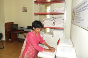 A print-disabled Woman standin infront of the table and reading.
